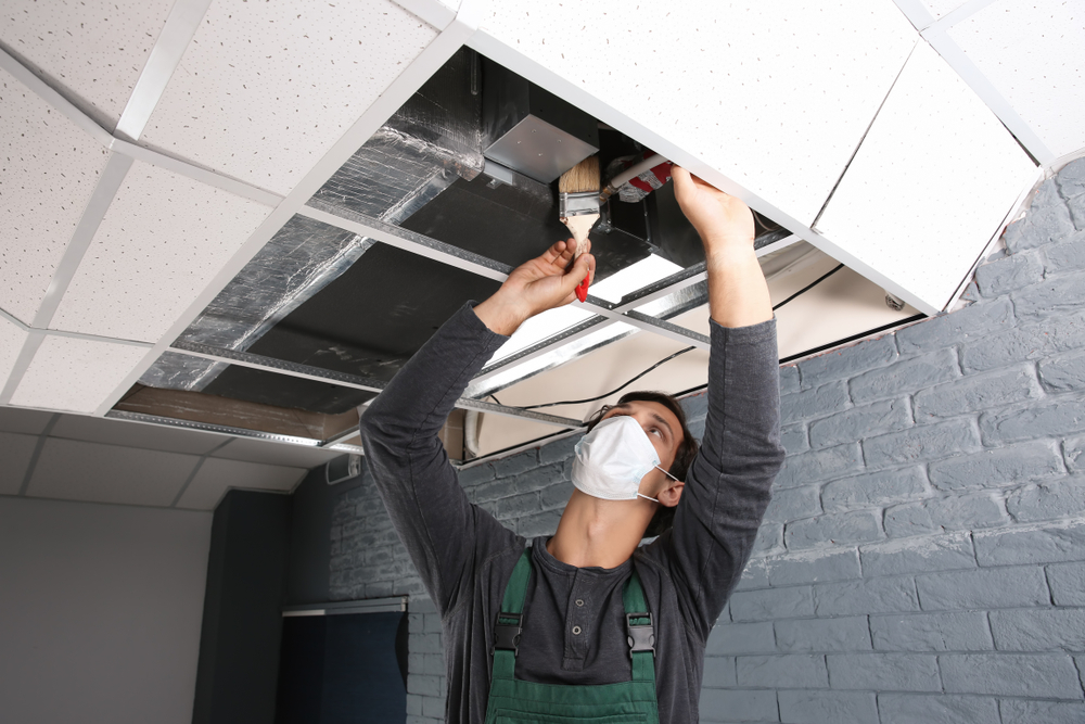 HVAC technician working on ceiling ductwork